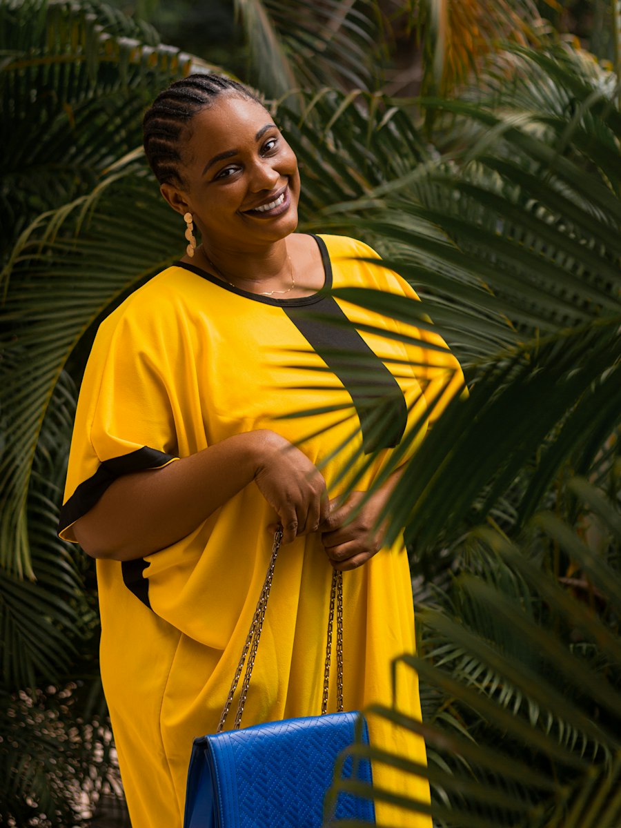 Smiling woman in a yellow kaftan among palm leaves