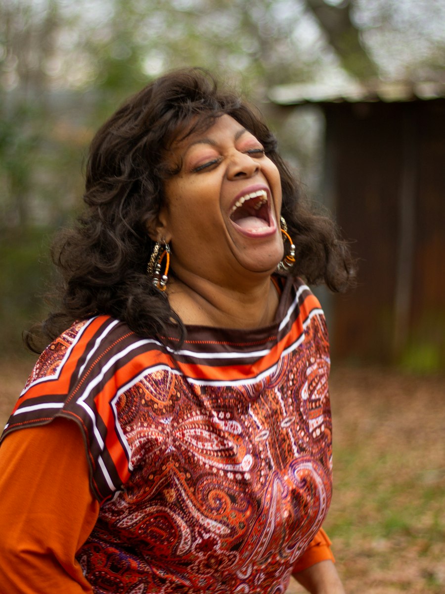 Woman laughing joyfully in an orange paisley top