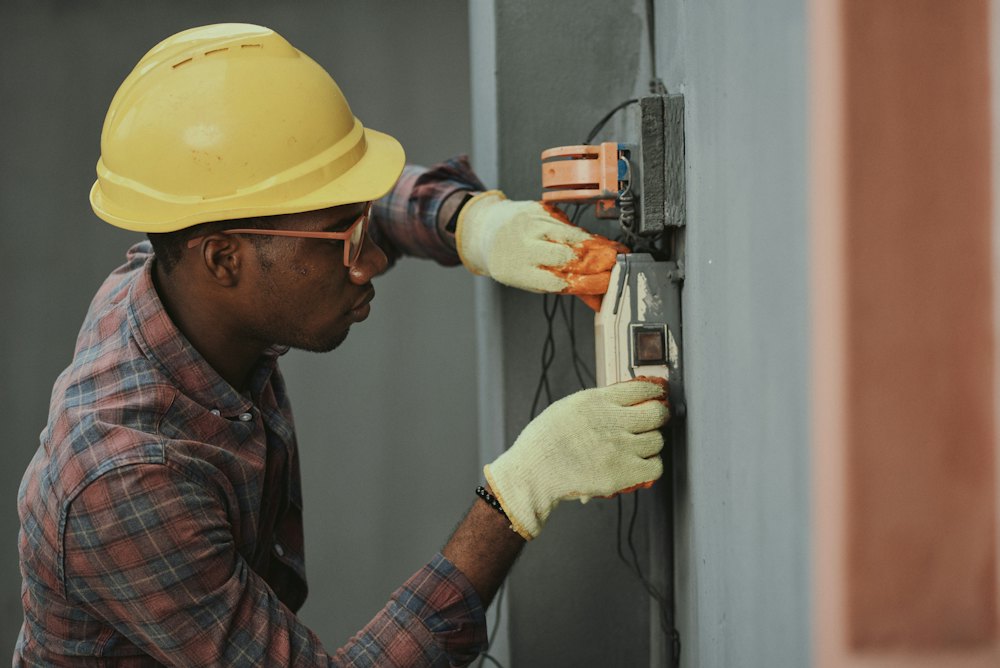 Electrician in a hard hat wiring a switch box