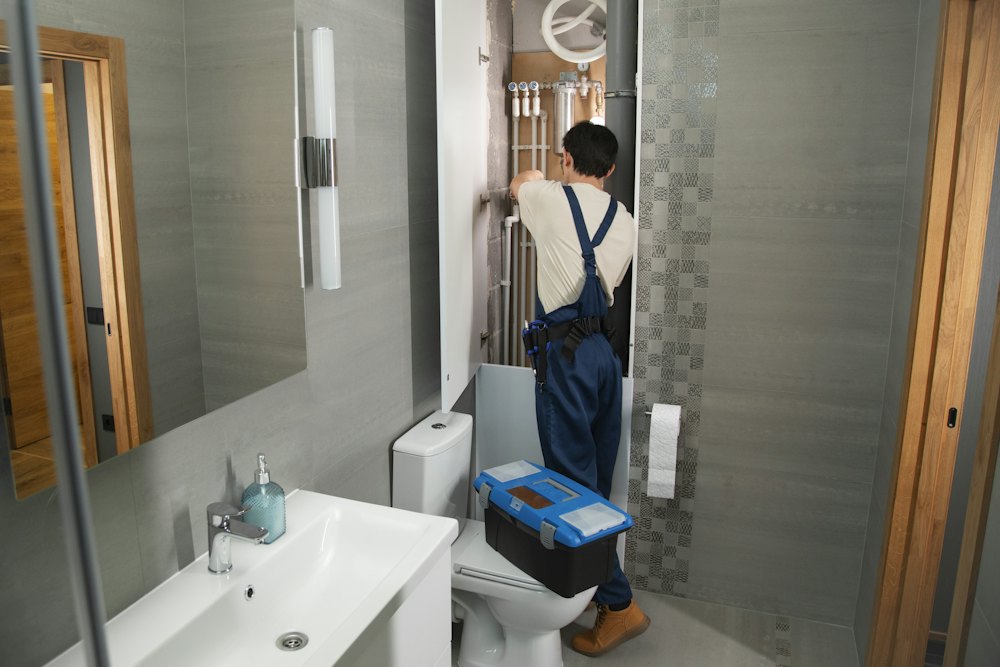 Plumber fitting pipes under a bathroom sink